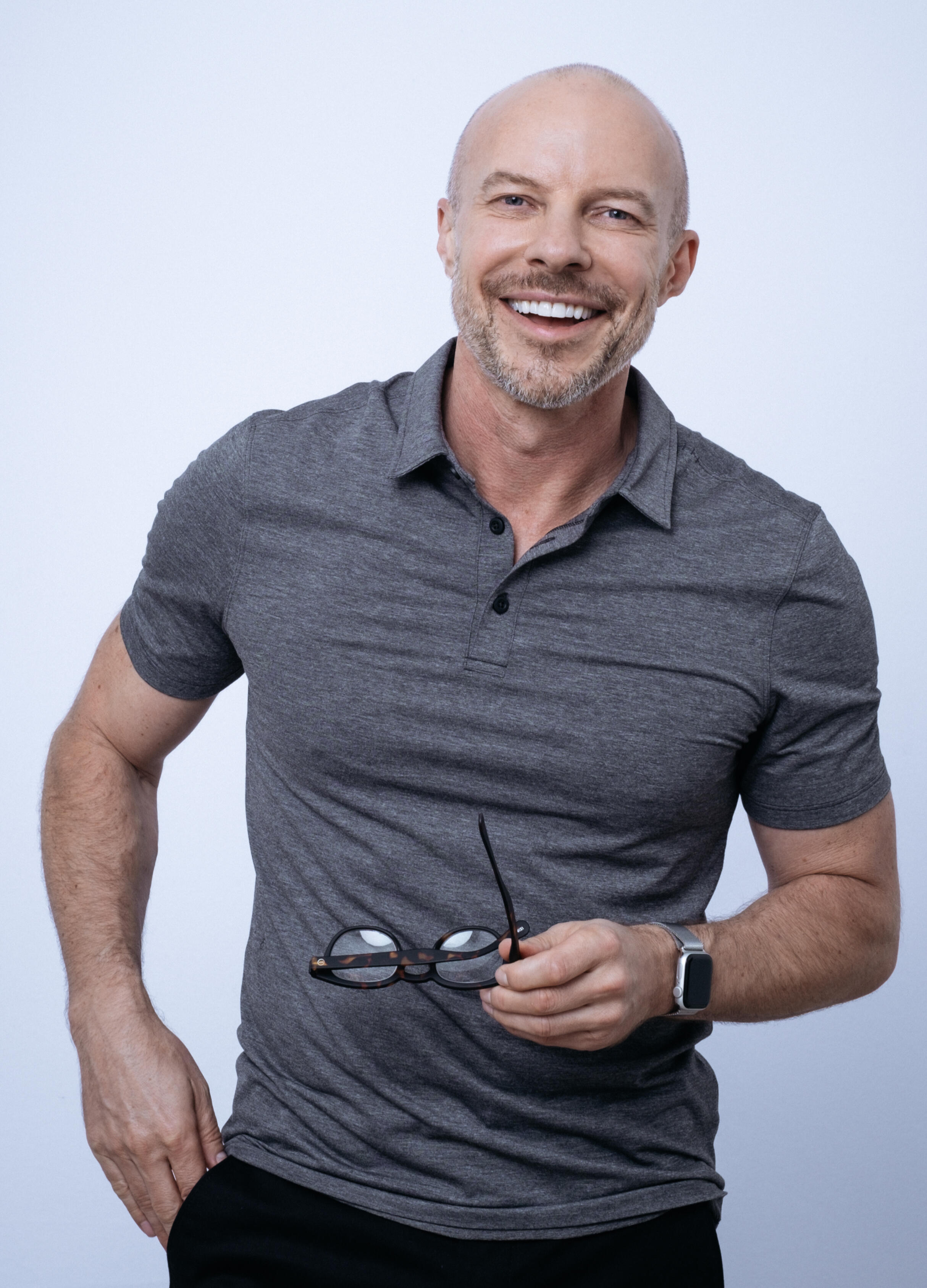 Presenter Gary Williams looking towards the camera in polo shirt holding spectacles.
